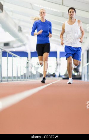 Couple running on indoor track in gym Stock Photo