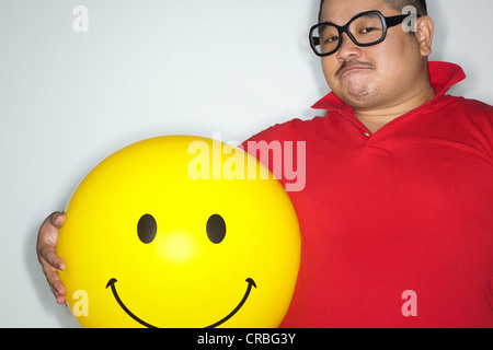 Portrait of a fat man holding yellow ball with smiley face Stock Photo