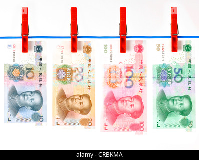 Row of Chinese yuan or renminbi banknotes, the currency of the People's Republic of China, hanging on a clothesline, symbolic Stock Photo