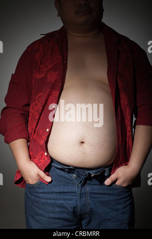 Overweight man in tight jeans at home. Weight loss concept Stock