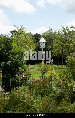 White birdhouse in lush garden Stock Photo