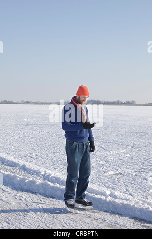 Man in ice skates using cell phone Stock Photo