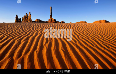 Sand dunes in front of Totem Pole and Yei Bi Chei rock formations after sunrise, Monument Valley, Navajo Tribal Park Stock Photo
