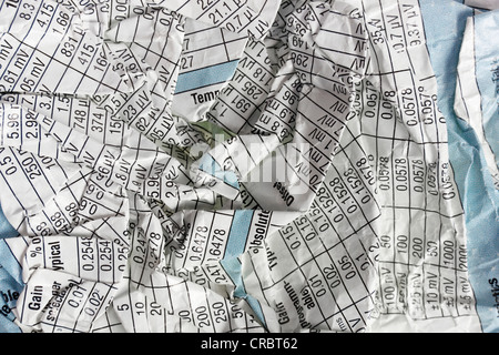 Deformation of the twisted torn crumpled page sheet of white paper. On a sheet of printed table with mass digital media data. Lo Stock Photo