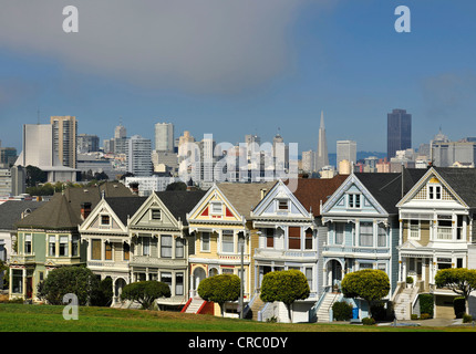 Painted Ladies, Victorian, multi-coloured wooden houses in front of the skyline with the Transamerica Pyramid, Steiner Street Stock Photo