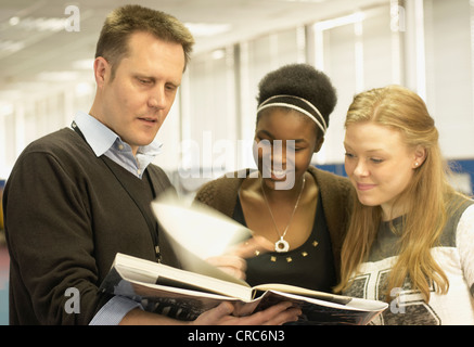 Students reading with teacher in library Stock Photo