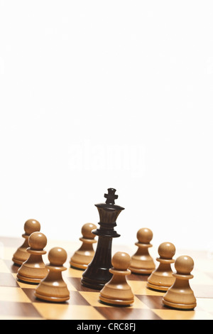 White pawns surrounding black chess king Stock Photo