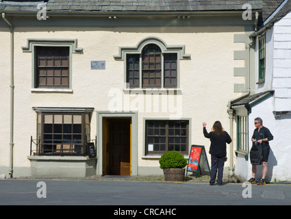 Man and woman outside the Beatrix Potter Galley in the village of Hawkshead, Lake District National Park, Cumbria, England UK Stock Photo