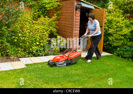 Mature woman mowing the lawn with an electric mower Stock Photo - Alamy