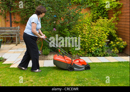 Mature woman mowing the lawn with an electric mower Stock Photo ...