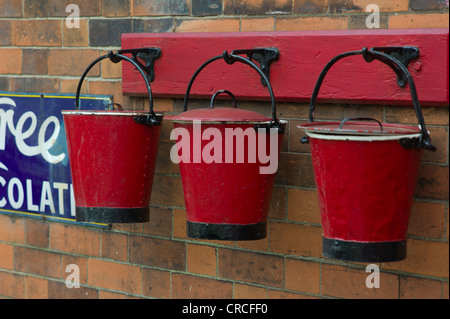Three red fire buckets hanging at a heritage railway station Stock Photo