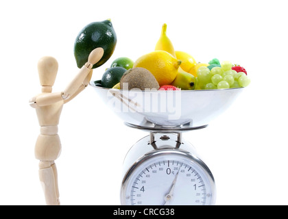 jointed doll taking fruit from scale Stock Photo