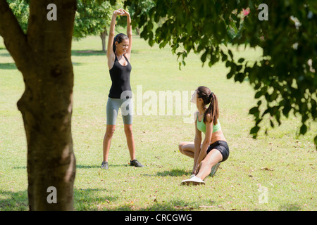 Two beautiful women stretching in city park after running and sport activity
