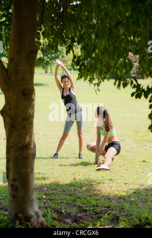 Two beautiful women stretching in city park after running and sport activity