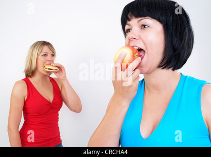 two women eating burger and apple Stock Photo