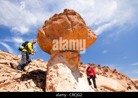 Trekkers in the Anti Atlas mountains of Morocco with a weathered pinnacle of rock. Stock Photo