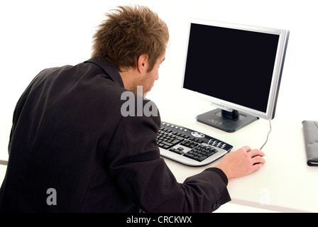 man sitting at a desk in front of a black screen Stock Photo