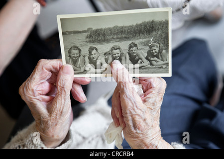 Viewing old photo, old lady's hands holding a historic black and white photography from 1940's, memories, historical photo Stock Photo