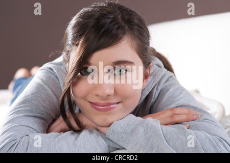 Smiling teenage girl lying on couch Stock Photo