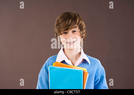 Smiling teenage boy holding folders, portrait Stock Photo