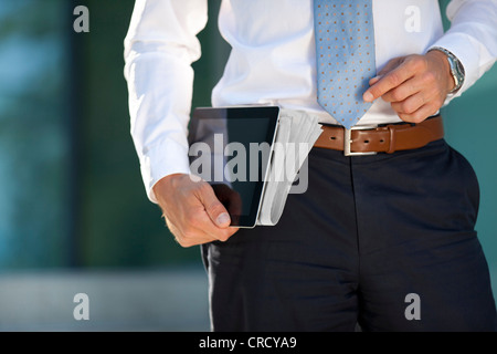 Businessman carrying tablet PC and newspaper under his arm Stock Photo