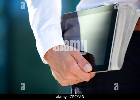 Businessman carrying tablet PC and newspaper under his arm Stock Photo