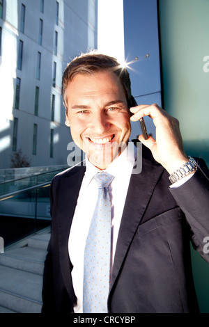 Smiling businessman on cell phone outdoors Stock Photo