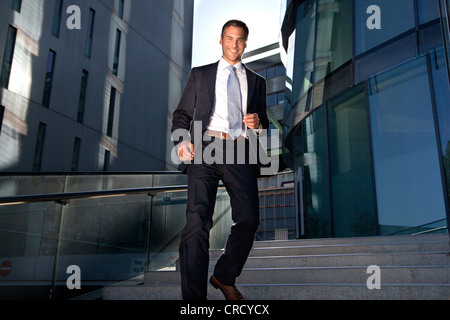 Smiling businessman walking down stairs Stock Photo