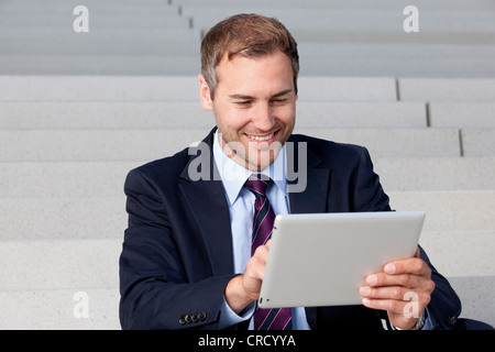 Businessman using tablet PC on stairs Stock Photo