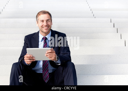Businessman using tablet PC on stairs Stock Photo