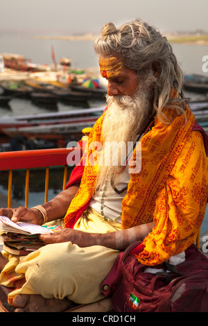 Sadhu (holy man) reading holy book  in Varanasi, Uttar Pradesh, India Stock Photo