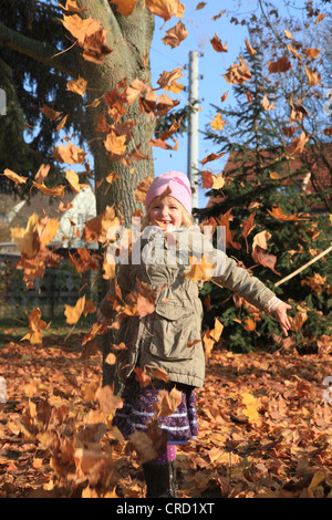 Girl playing in falling Autumn leaves Stock Photo - Alamy