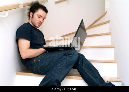 young man using his laptop on stairs Stock Photo