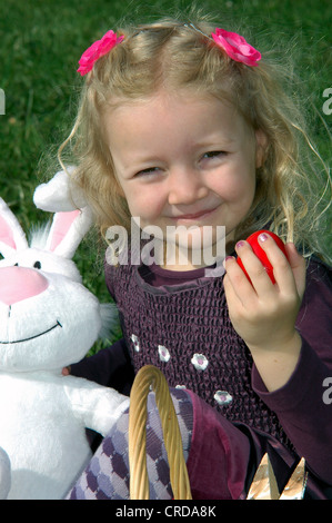 girl with Easter rabbit and Easter egg on a meadow Stock Photo