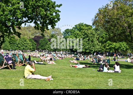 Crowds sunbathing and relaxing in sunshine St James Park London England Europe Stock Photo
