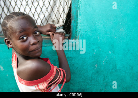 A girl looks back while watching TV through a window in the West Point slum of Monrovia, Montserrado county, Liberia on Monday A Stock Photo