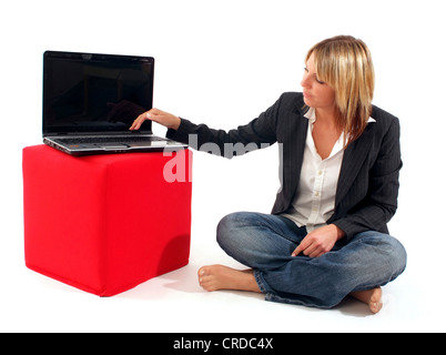 young business woman next to laptop on a red cube Stock Photo