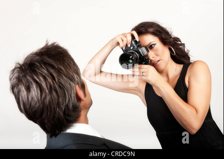 Young woman photographing a man with an old analog Nikon camera Stock Photo