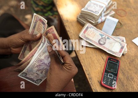 A staff member from a local bank counts money during a social cash transfer programme distribution in the village of Julijuah Stock Photo