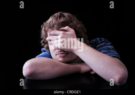 Young man covering face with his hand Stock Photo