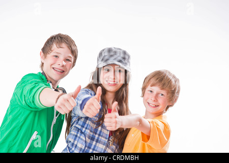 Three friends, one girl and two boys, giving thumbs up Stock Photo