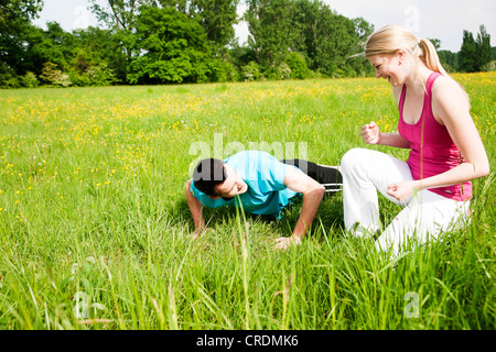 Young woman looking at her boyfriend who is doing push-ups Stock Photo