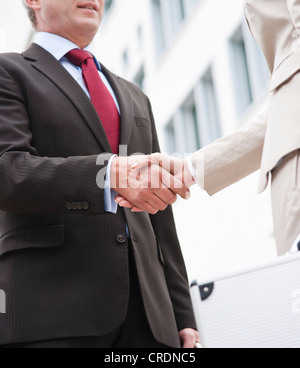Businessman and businesswoman shaking hands in front of an office building Stock Photo