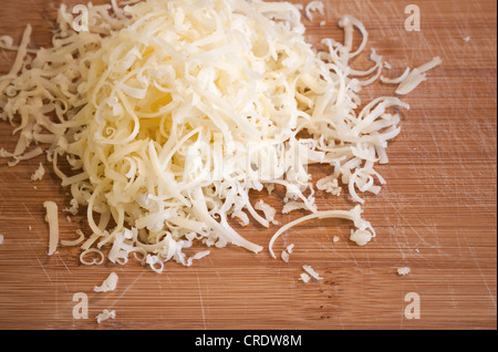 Pile of fresh grated cheese on wooden table Stock Photo