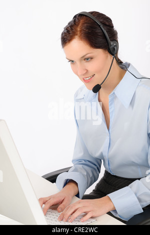 Friendly help desk woman at call center sitting behind computer Stock Photo