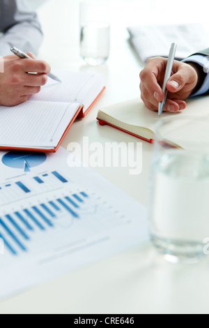 A closeup shot of female hands writing with a pencil on a ruled notepad ...