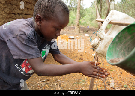 A boy washes his hands at a pedal-activated hand washing station outside a home latrine in the village of Kawejah Stock Photo