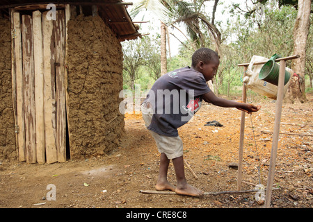 A boy washes his hands at a pedal-activated hand washing station outside a home latrine in the village of Kawejah Stock Photo