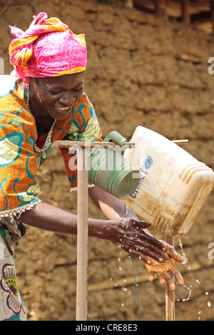 Community volunteer Hawa Kiadii washes her hands at a pedal-activated hand washing station outside a home latrine Stock Photo