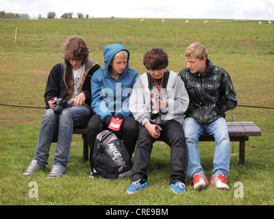 Teen male tourists looking over electronic audio guide at Stonehenge, England, May 16, 2012, © Katharine Andriotis Stock Photo